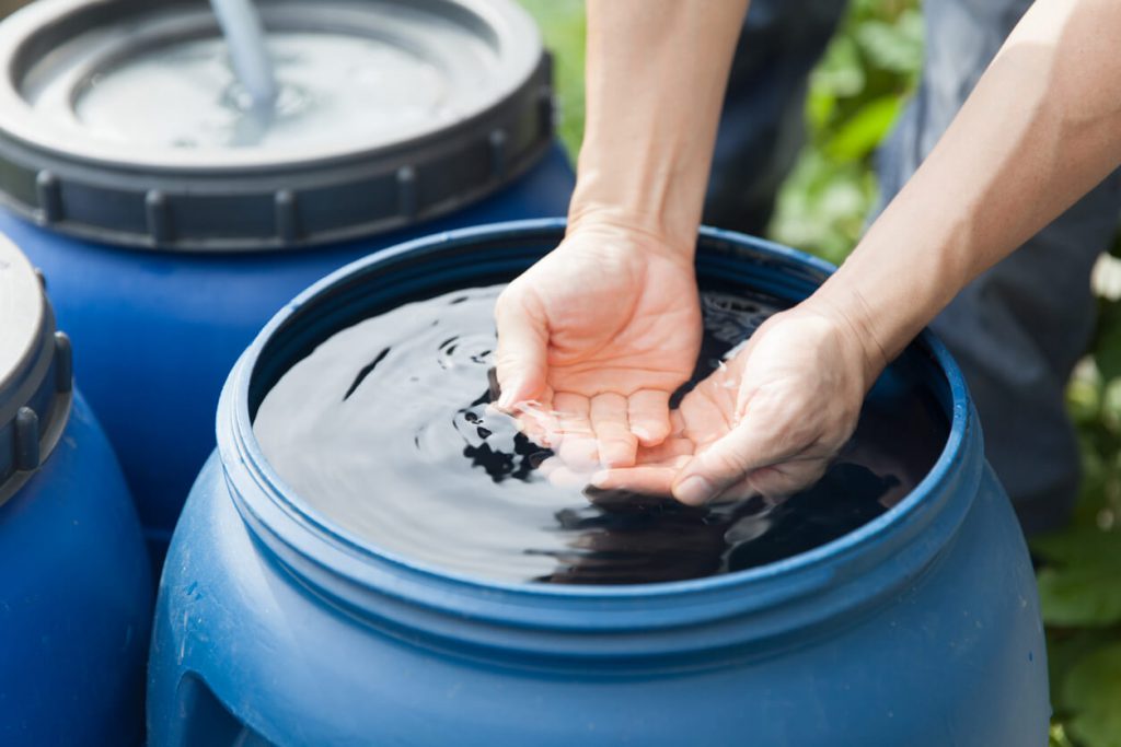 Hands touching rainwater in tank