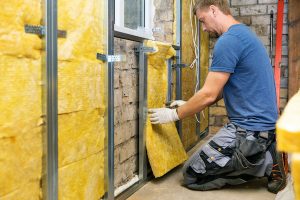 A construction worker insulating brick wall with glass wool