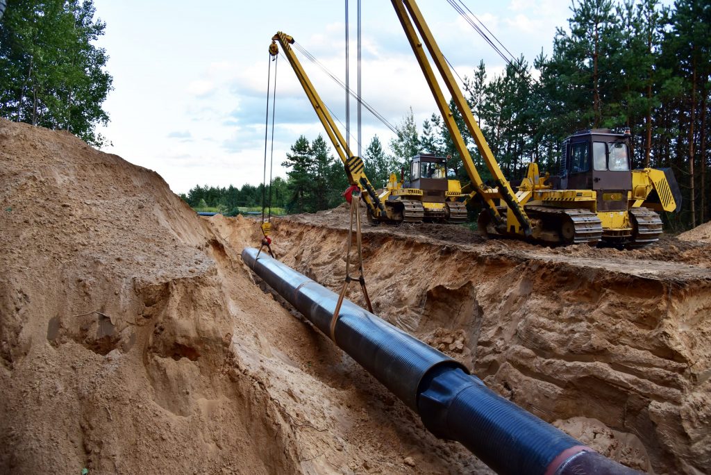 A section of an oil pipe line being assembled in the ground by two large backhoes