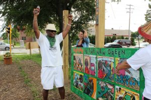 People in a Milwaukee community celebrating their rain management program outdoors in front of a hand painted sign