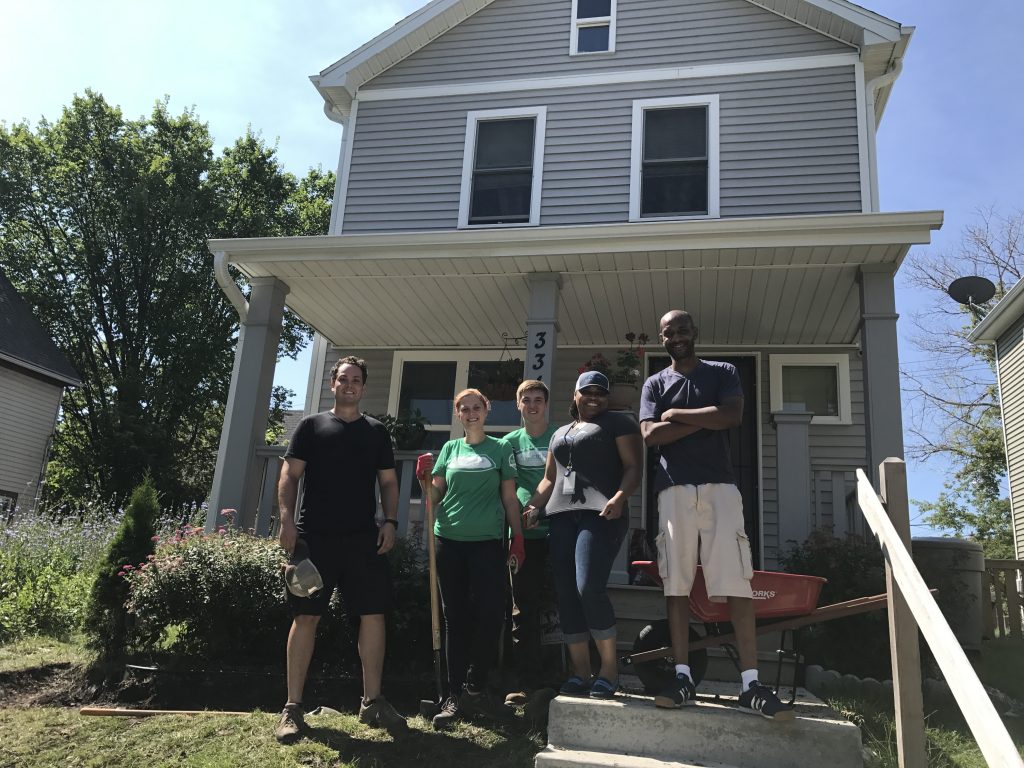 Five Milwaukee community members posing in front of a house where they are planting a rain garden