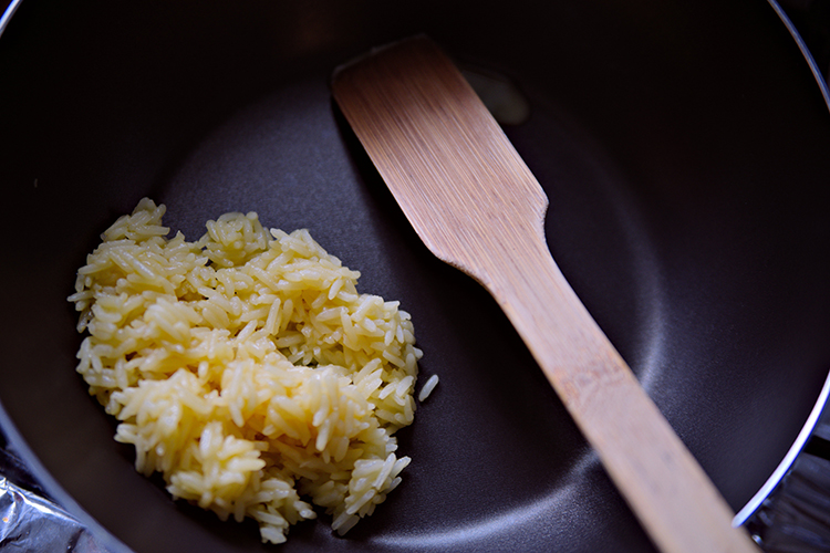 A teflon cooking pan with rice and a spatula in it