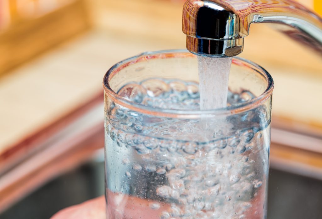 Closeup of glass filling with fresh water from a kitchen faucet