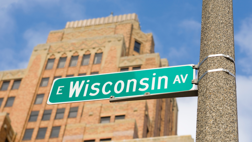 A street sign that reads "Wisconsin Avenue" set in front of a multi-story building.