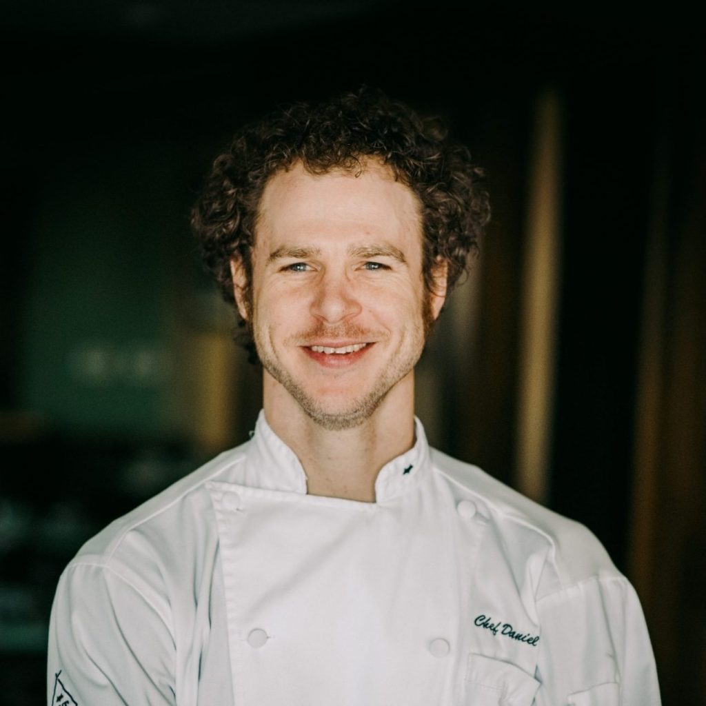 Chef Dan Fox stands with his arms crossed, smiling