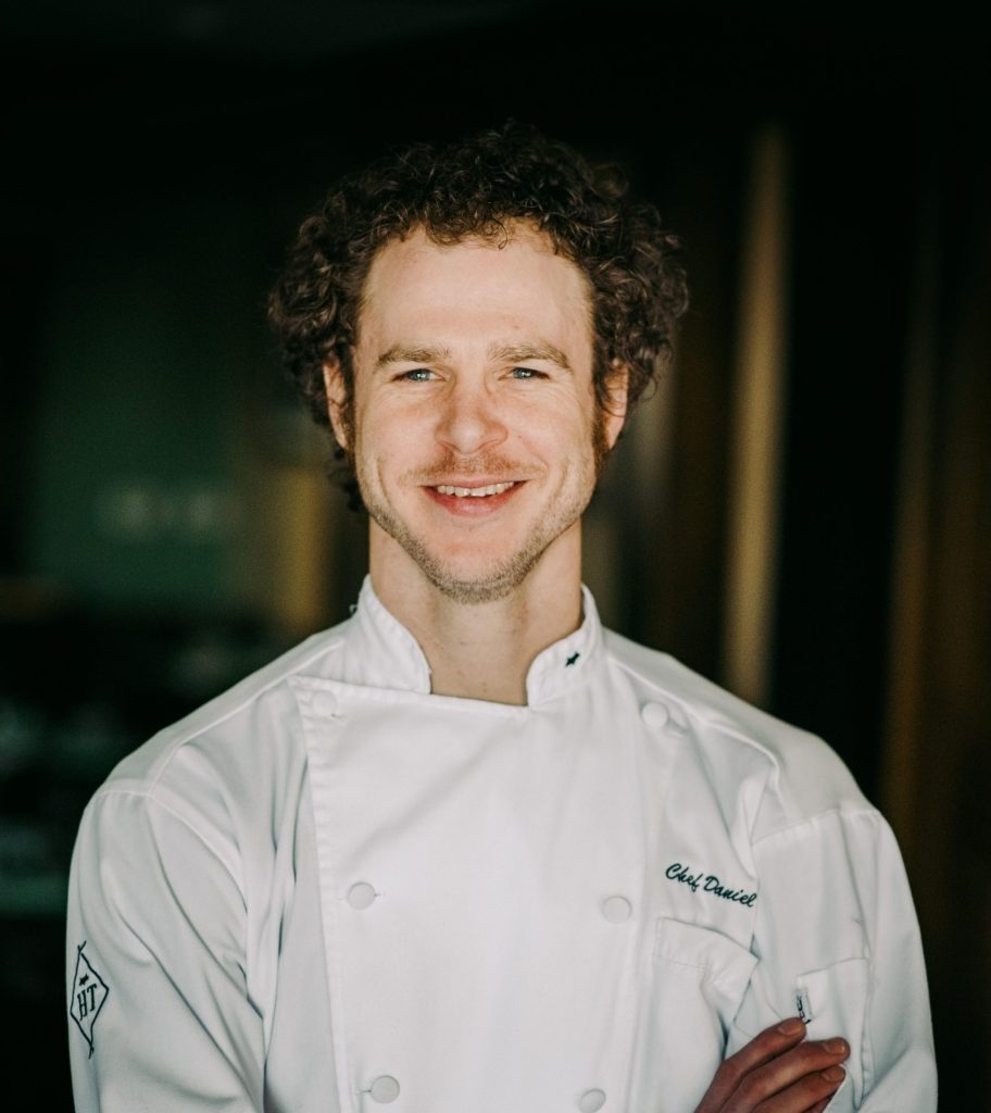 Chef Dan Fox stands with his arms crossed, smiling