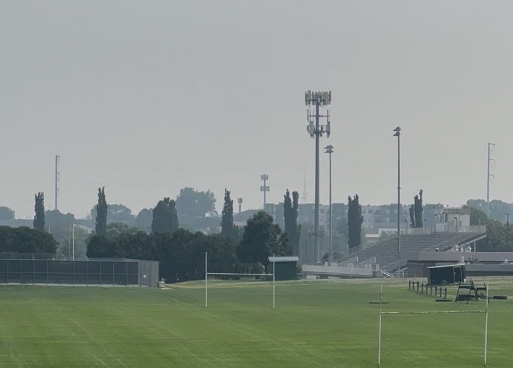 Park with hazy buildings in the distance blanketed by wildfire smoke