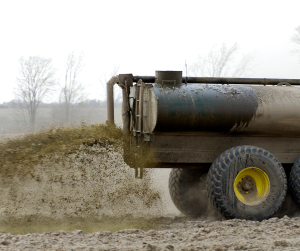 Truck spreads animal waste/manure on farm field