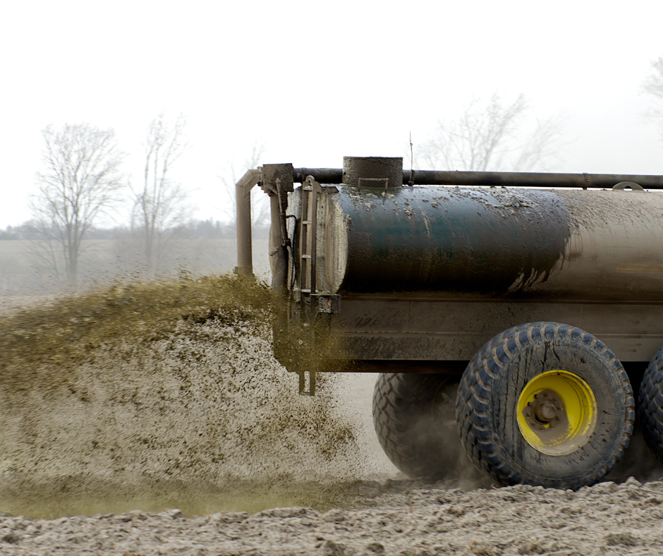 Truck spreads animal waste/manure on farm field