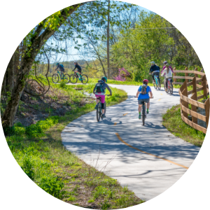 A bike path through a rural park with people walking and biking along it