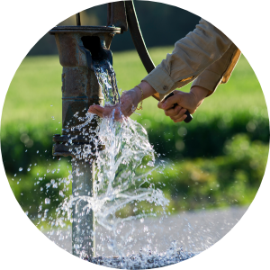 Hands pumping water out of a well faucet