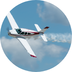 A small aircraft flies through the blue skies with a trail of smoke behind it