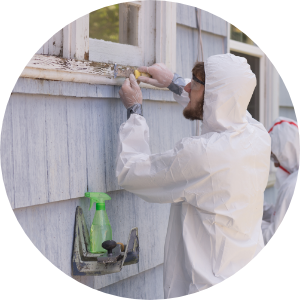 Workers in hazmat suits scraping lead paint from the exterior of a home